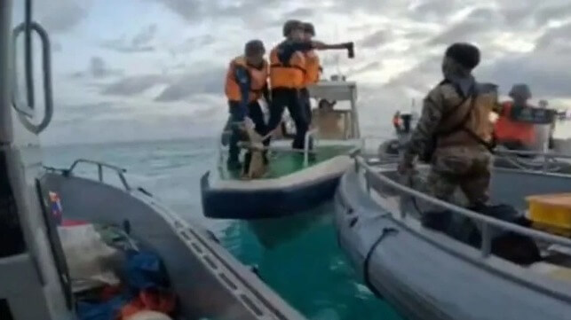 A China Coast Guard servicemember threatens a Philippine soldier with an axe, June 17 (AFP)